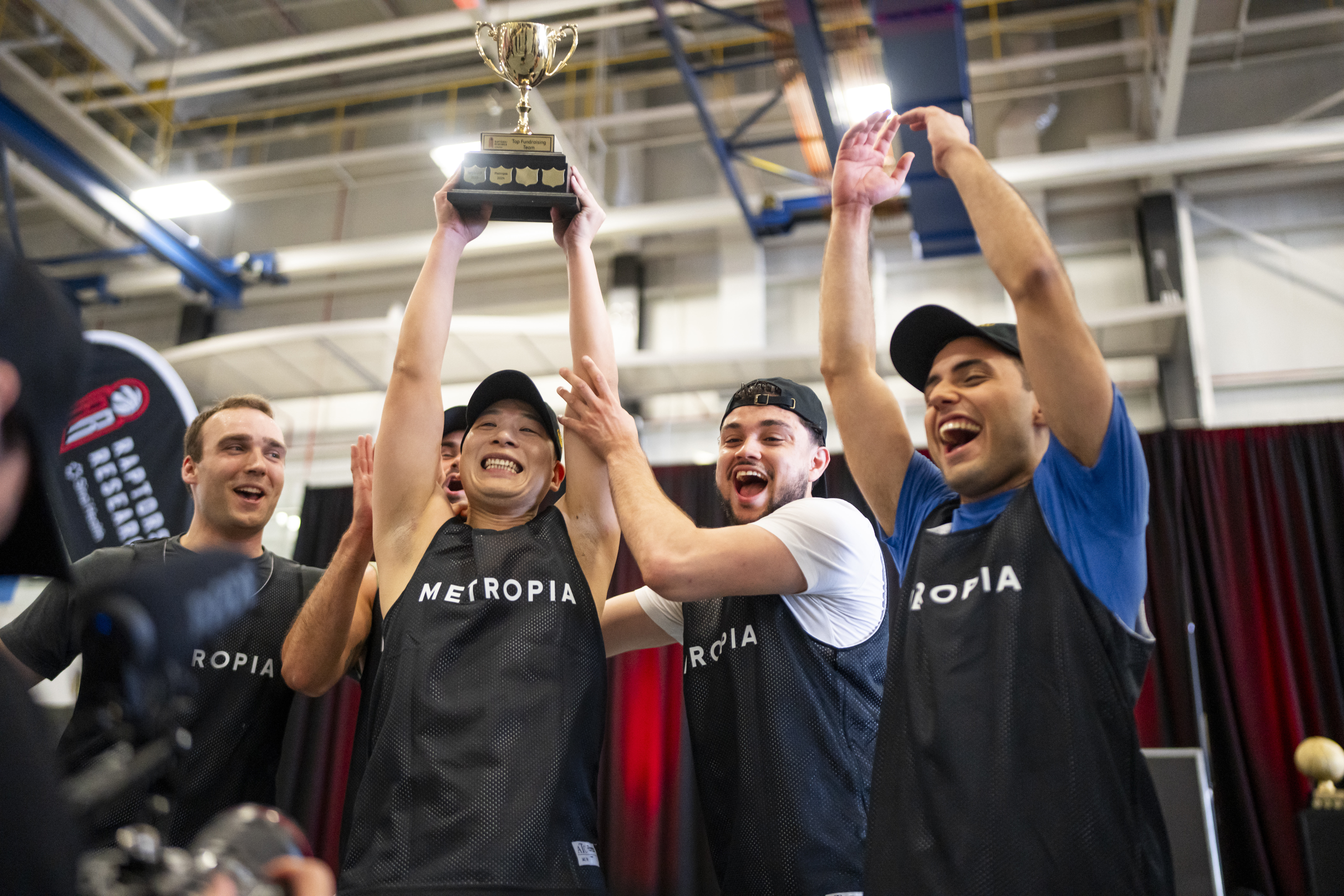 group of team members holding trophy and fundraising cheque